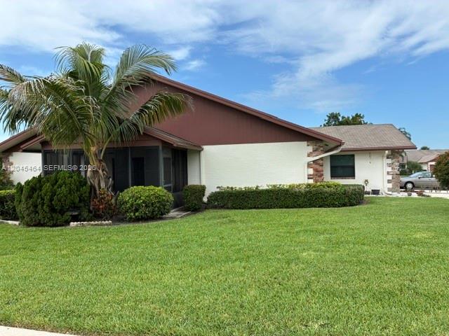 The exterior of a house features a screened-in porch, brown siding, and landscaped bushes — 100 S Moccasin Trl S, Jupiter FL 33458, JUPITER, FL