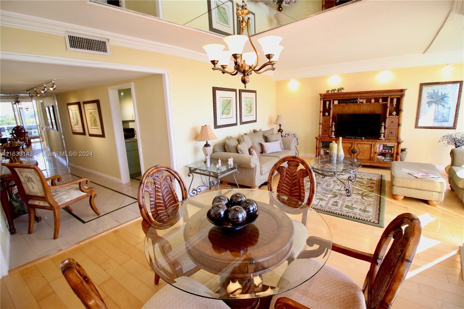A dining area with a glass table opens into a living room with wooden furniture — 900 Bay Dr # 319, Miami Beach FL 33141, MIAMI BEACH, FL