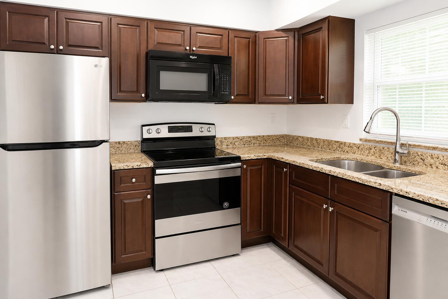 A kitchen with dark wood cabinets, stainless steel appliances, and speckled granite countertops — 92 Lariat Circle, Boca Raton FL 33487, BOCA RATON, FL