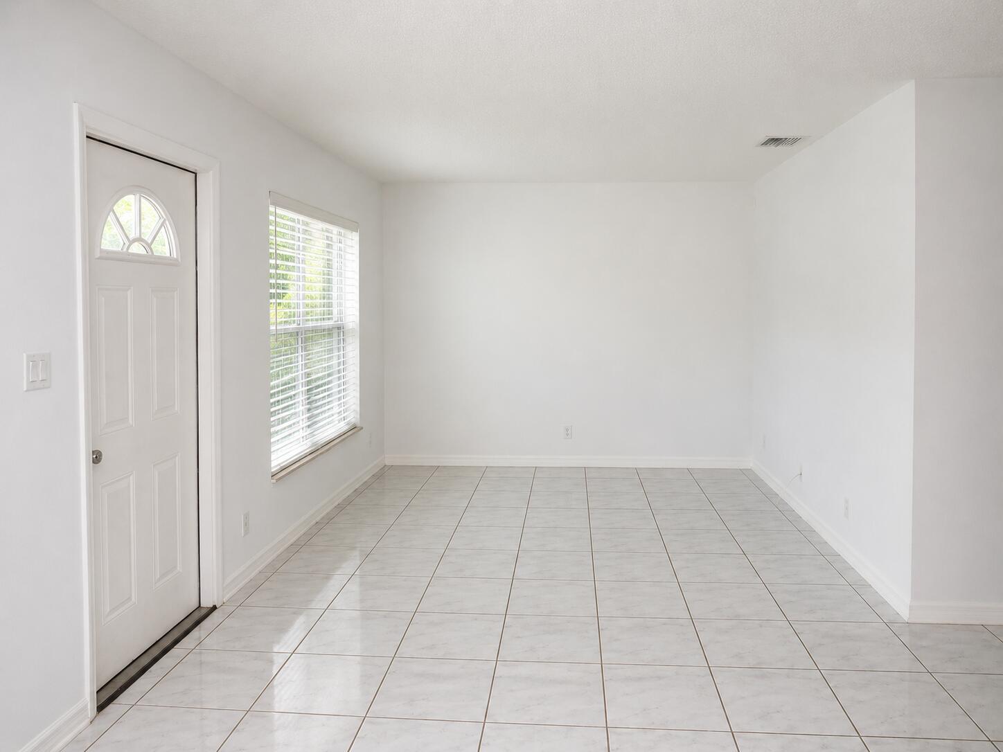 An empty room with white walls, tiled flooring, a front door, and a window — 92 Lariat Circle, Boca Raton FL 33487, BOCA RATON, FL