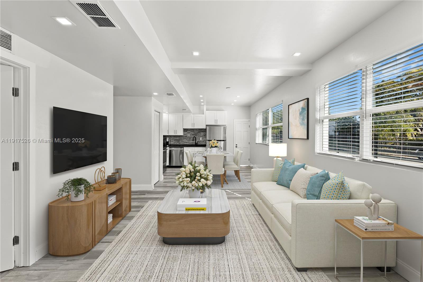 This is a digitally staged living room and kitchen area with light wood-look flooring — 305 NW 58th St, Miami FL 33127, MIAMI, FL