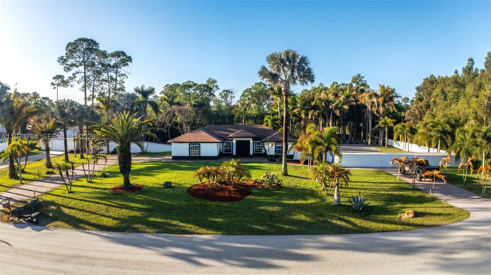 An aerial view shows a white house with a brown roof surrounded by palm trees — 15780 N 75th Ln N, Loxahatchee FL 33470, LOXAHATCHEE, FL