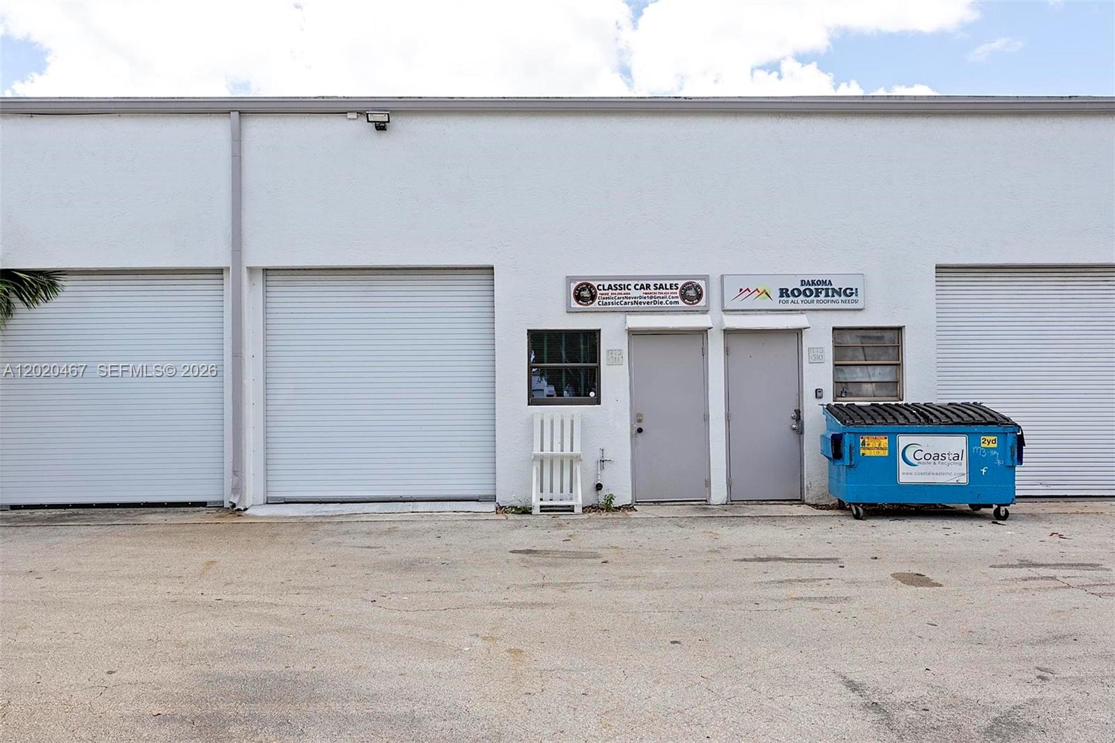 The exterior of a commercial building features three roll-up doors, two entry doors, and a dumpster — 1773 Blount Rd # 311, Pompano Beach FL 33069, POMPANO BEACH, FL