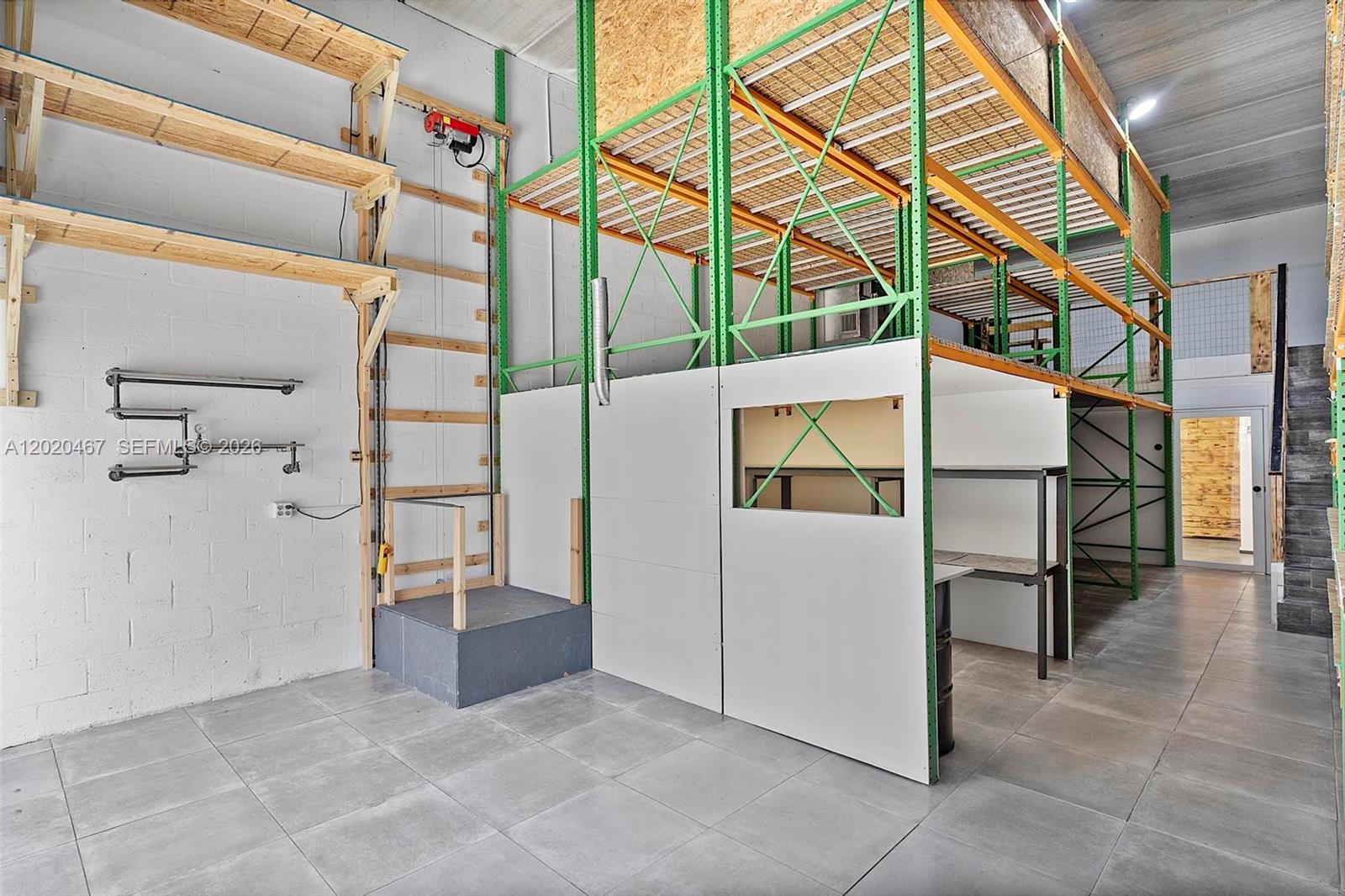 An industrial space features a mezzanine storage rack system, a small hoist, and tiled floors — 1773 Blount Rd # 311, Pompano Beach FL 33069, POMPANO BEACH, FL