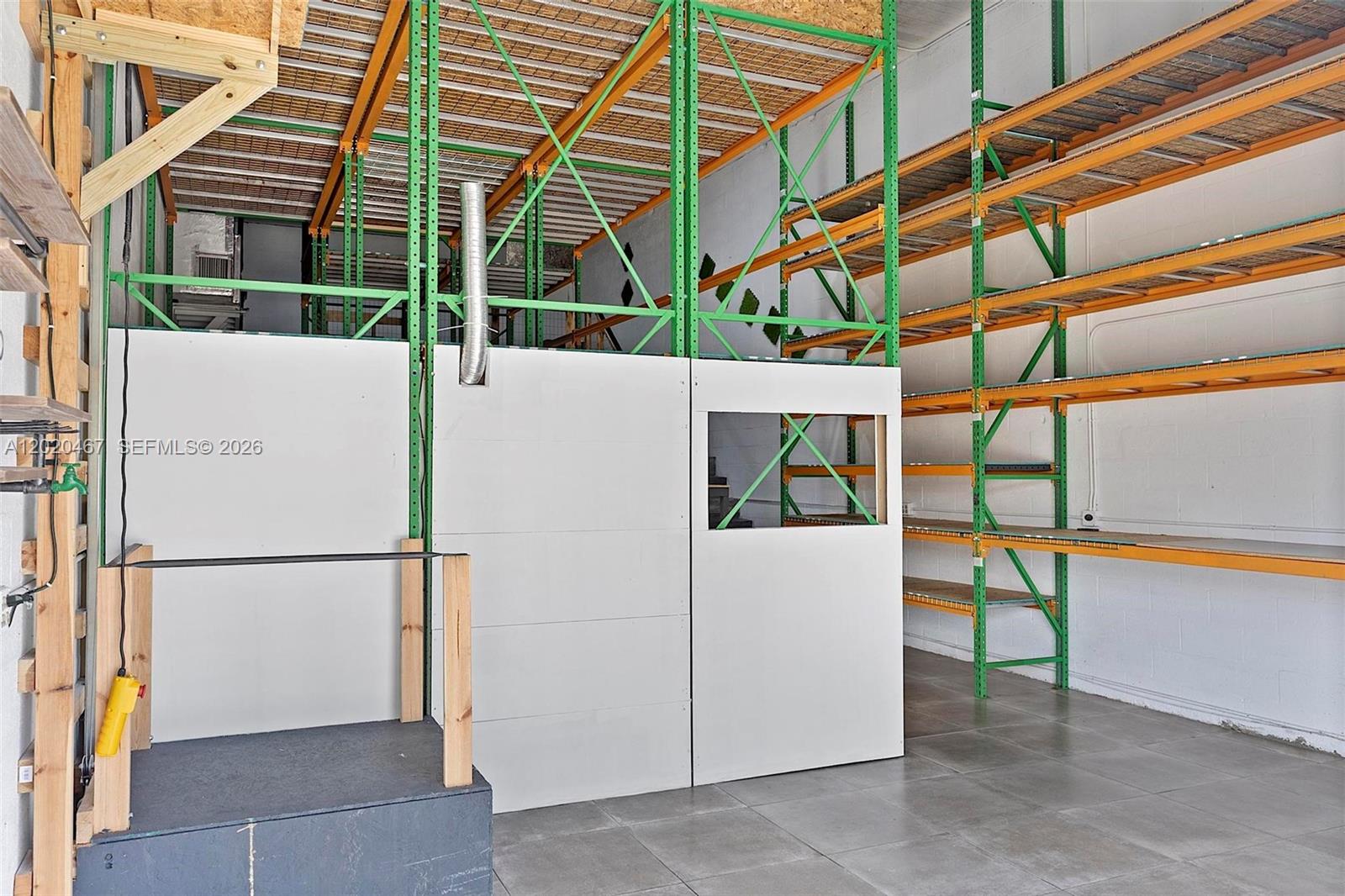 A warehouse space features tall green metal shelving units and a small enclosed office area — 1773 Blount Rd # 311, Pompano Beach FL 33069, POMPANO BEACH, FL