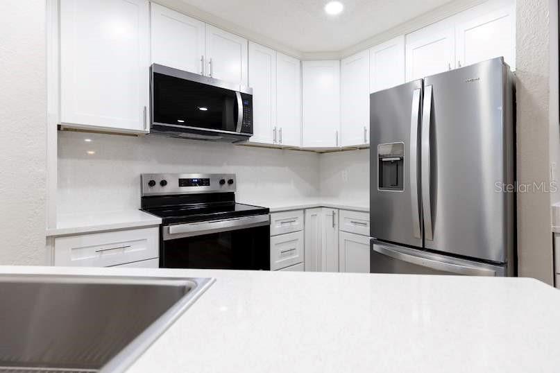 A kitchen with white cabinets, stainless steel appliances, and white countertops — 4572 COMMANDER DRIVE UNIT 1212, ORLANDO, FL