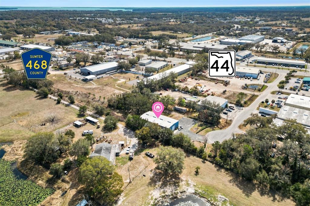 This aerial view shows a commercial building with a pink location pin near a highway — 118 WEBER AVENUE, LEESBURG, FL
