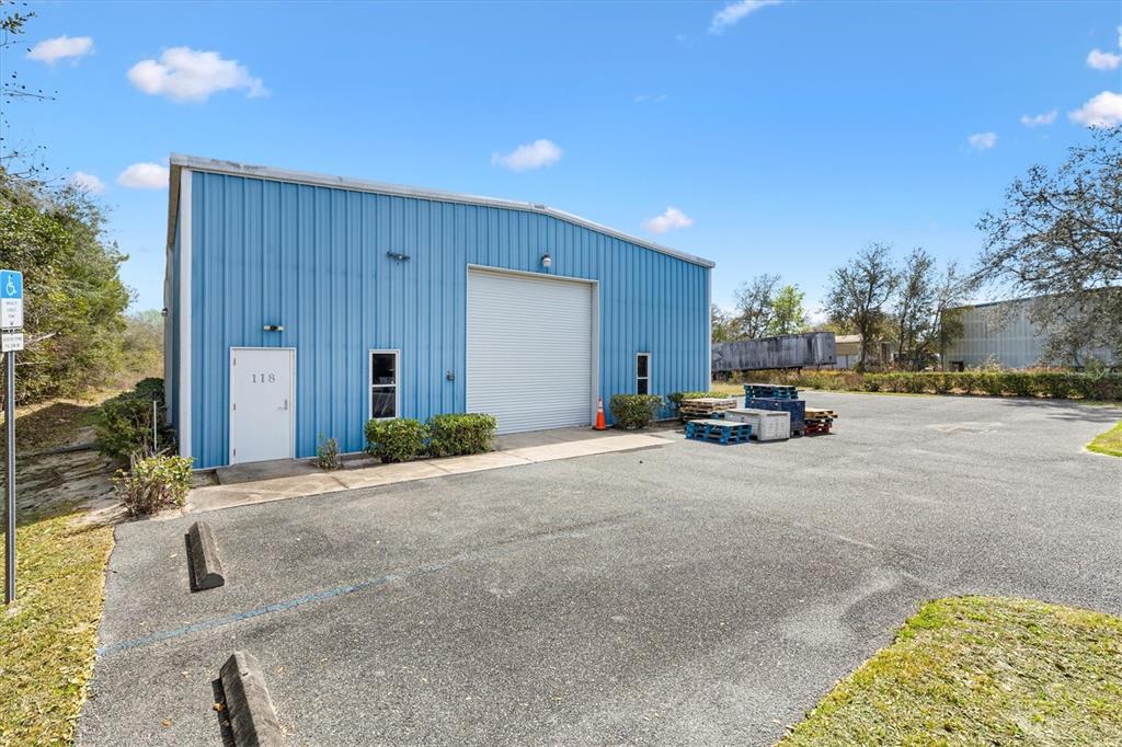 A blue metal industrial building with a roll-up door and a single entrance door — 118 WEBER AVENUE, LEESBURG, FL