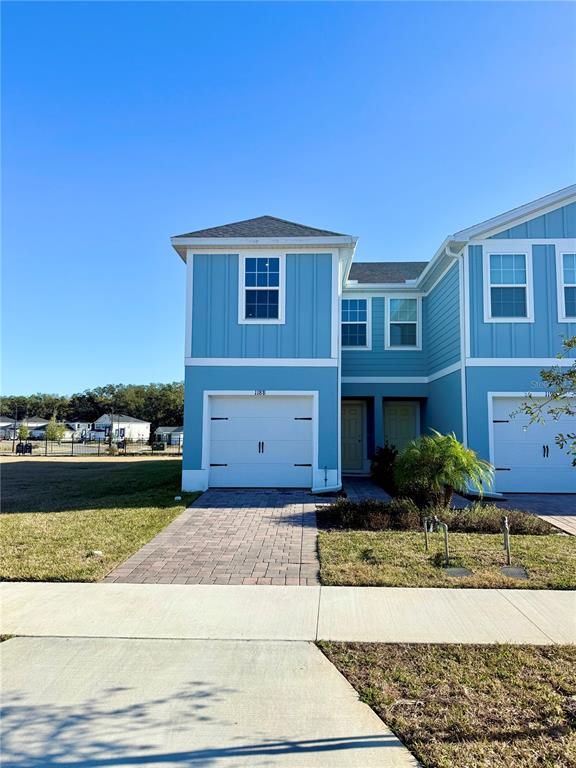 A blue two-story townhouse features a white garage door and a paved driveway — 1188 PORT BLUE WAY, LADY LAKE, FL