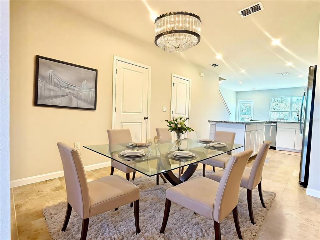 A dining room features a glass table, six chairs, a crystal chandelier, and tile flooring — 1188 PORT BLUE WAY, LADY LAKE, FL