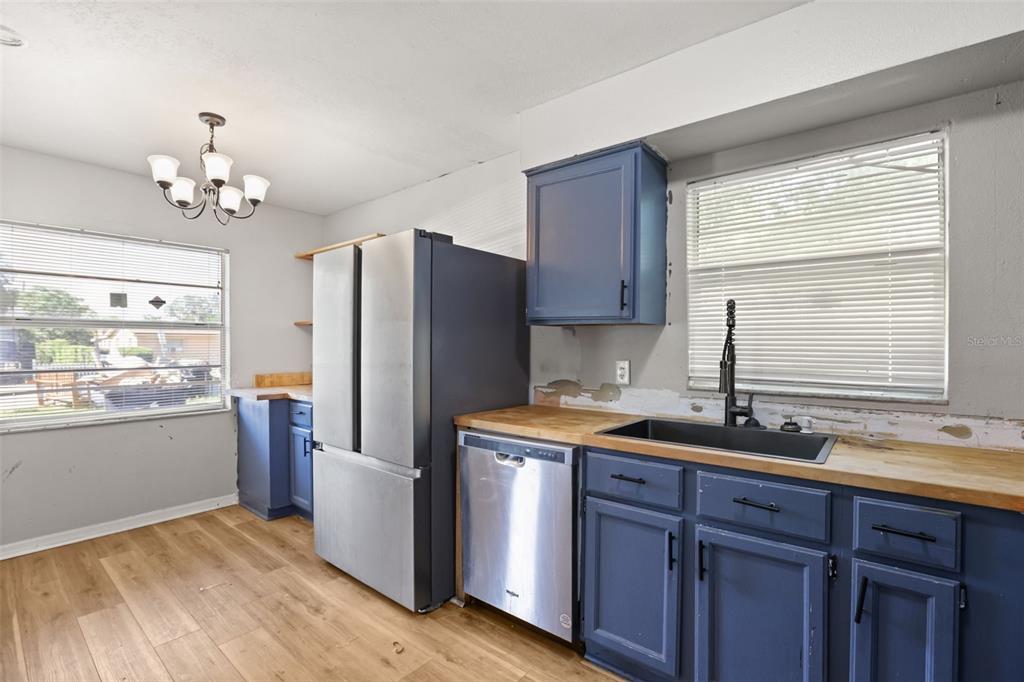 A kitchen features blue cabinets, stainless steel appliances, a butcher block countertop, and wood flooring — 3469 JANET STREET, APOPKA, FL