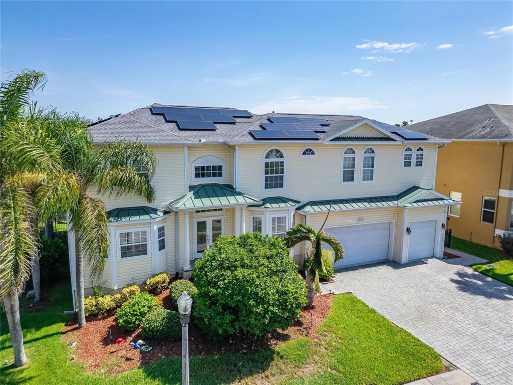 A two-story yellow house with a shingled roof, solar panels, and a three-car garage — 339 MANATEE LANE, TARPON SPRINGS, FL