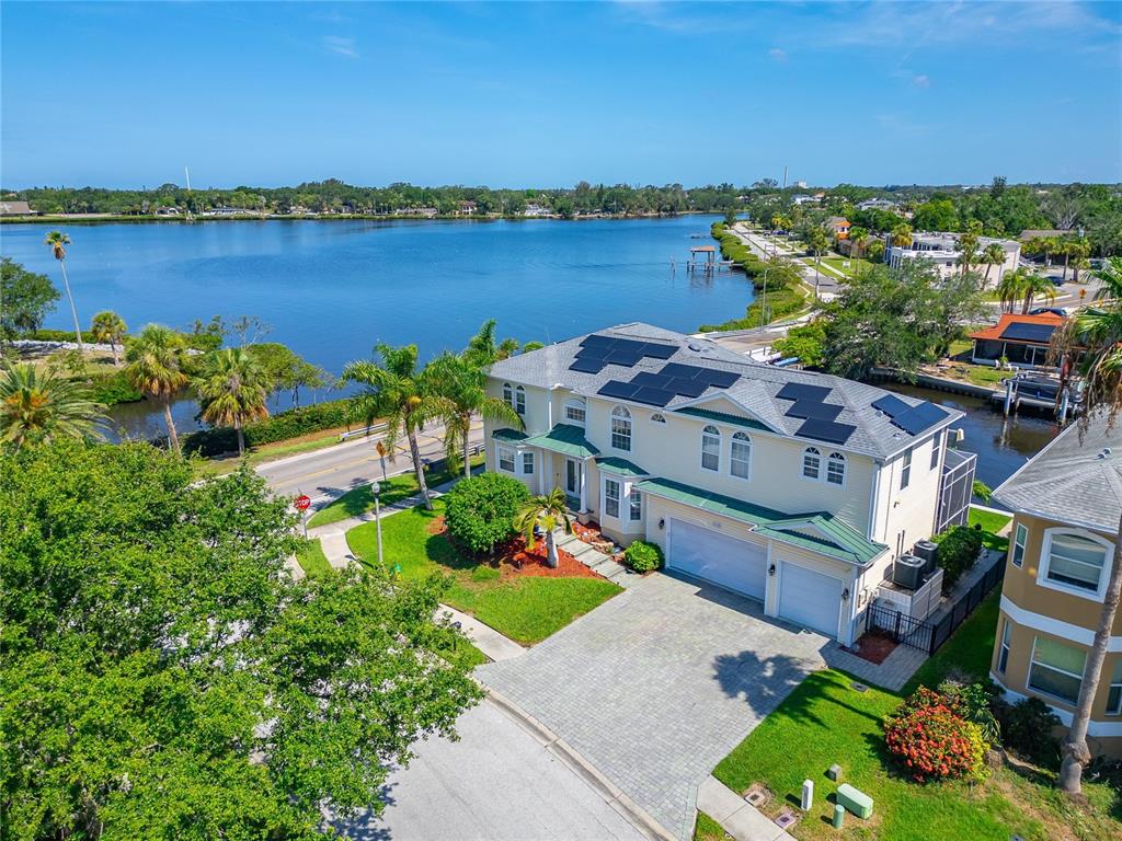 An aerial view shows a two-story house with solar panels near a large lake — 339 MANATEE LANE, TARPON SPRINGS, FL