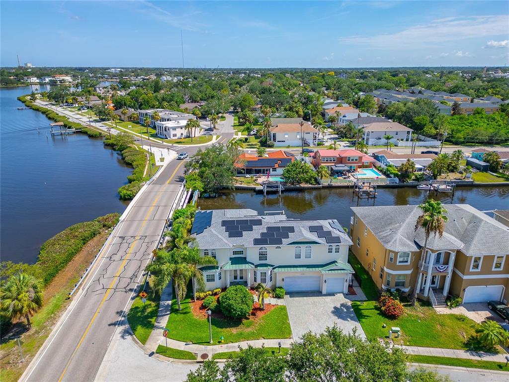 An aerial view shows a waterfront house with solar panels next to a road bridge — 339 MANATEE LANE, TARPON SPRINGS, FL