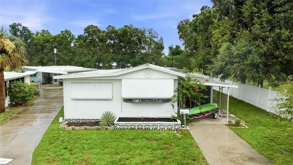A white mobile home with a green kayak on a trailer parked in the carport — 1891 ENGLEWOOD ROAD UNIT 167, ENGLEWOOD, FL
