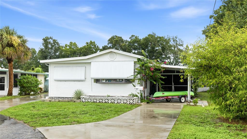 A white mobile home with a carport and a boat on a trailer in front — 1891 ENGLEWOOD ROAD UNIT 167, ENGLEWOOD, FL