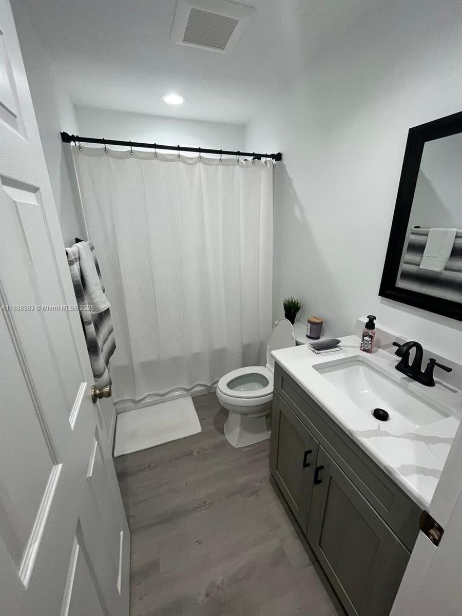 A bathroom features a gray vanity, a white countertop, a toilet, and a shower curtain — 5218 SE 43 St, Okeechobee FL 34974, OKEECHOBEE, FL