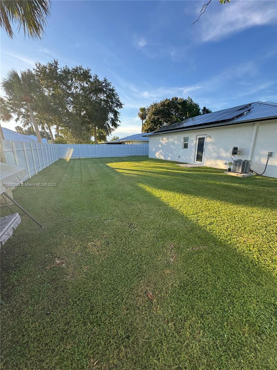 A grassy backyard features a white vinyl fence and the side of a house — 5218 SE 43 St, Okeechobee FL 34974, OKEECHOBEE, FL