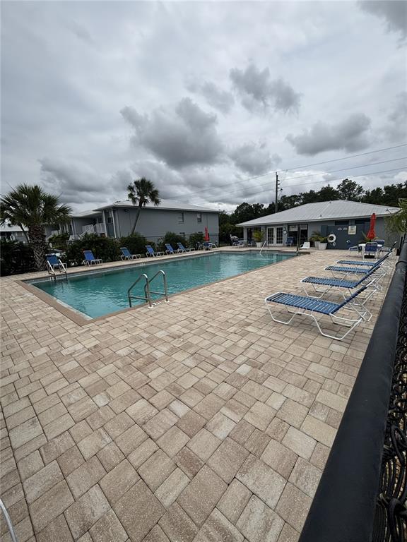An outdoor swimming pool with lounge chairs on a paved deck near a building — 25050 SANDHILL BOULEVARD UNIT 1A3, PUNTA GORDA, FL