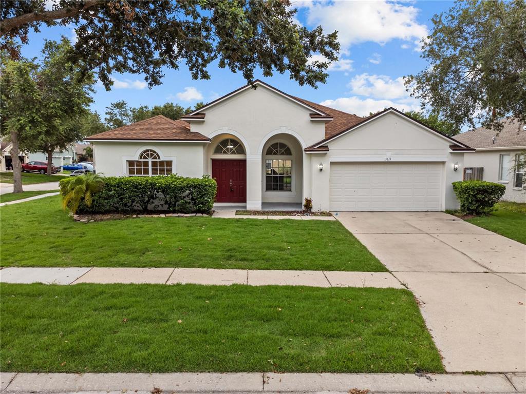 A single-story house with a white stucco exterior, red double doors, and a two-car garage — 11611 JORDANS LANDING COURT, RIVERVIEW, FL