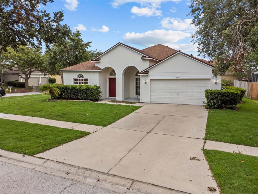 A single-story house with a white stucco exterior, a red front door, and a two-car garage — 11611 JORDANS LANDING COURT, RIVERVIEW, FL