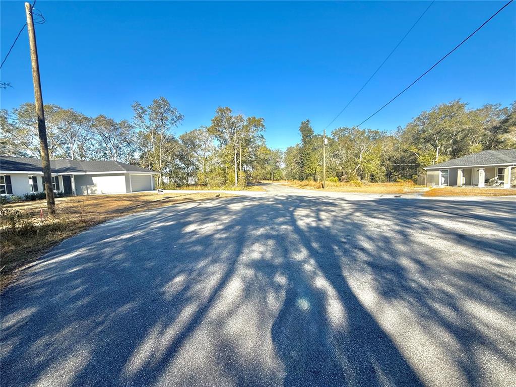 A paved street intersection is flanked by two houses and surrounded by trees — TBD LOT 35 LOCUST PASS COURT, OCALA, FL