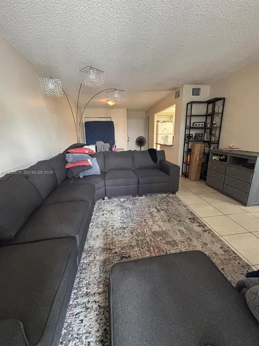 A living room features a large gray sectional sofa, a patterned rug, and tile flooring — 2029 NW 46th Ave # E305, Lauderhill FL 33313, LAUDERHILL, FL