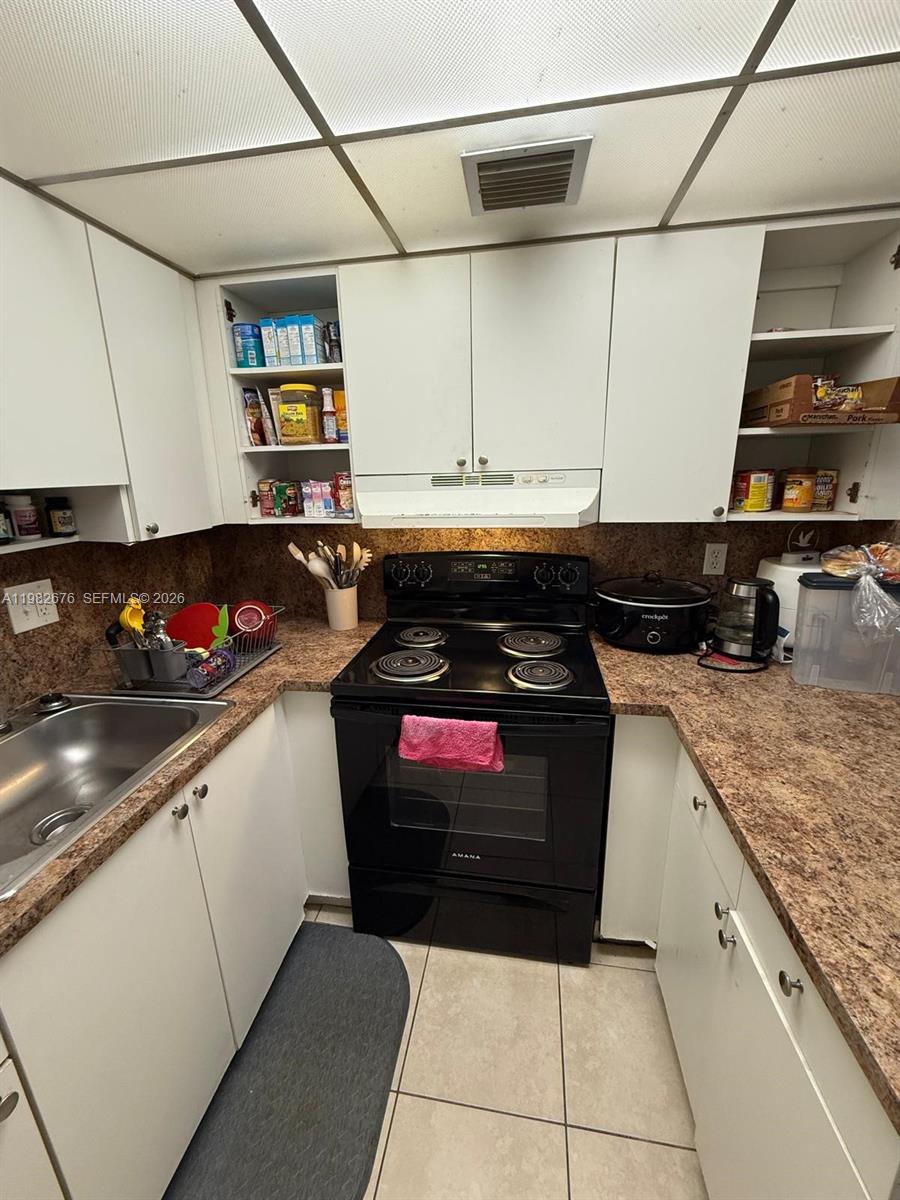 A small kitchen features white cabinets, a black electric stove, and brown laminate countertops — 2029 NW 46th Ave # E305, Lauderhill FL 33313, LAUDERHILL, FL