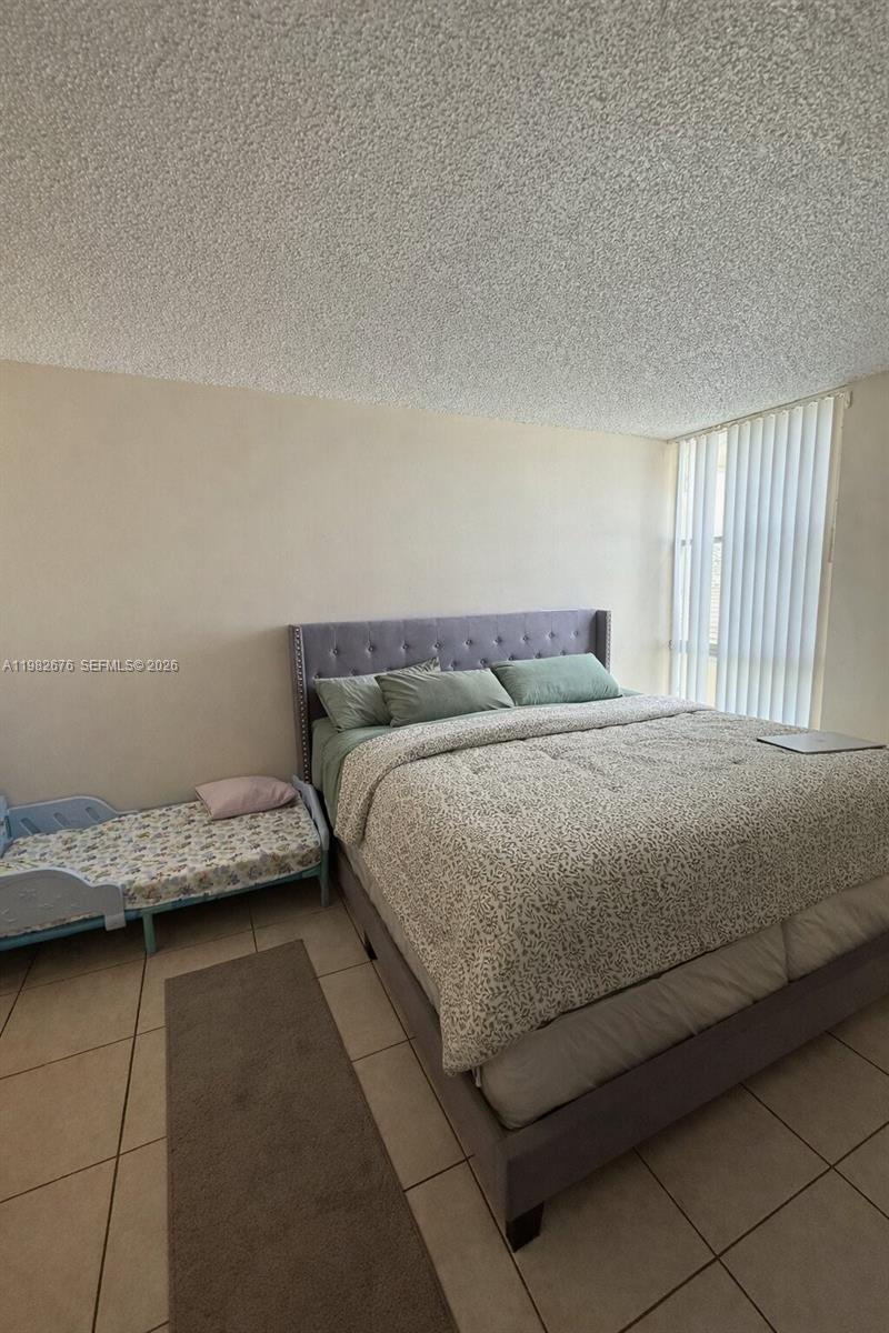 A bedroom features a large bed, a small toddler bed, and tile flooring — 2029 NW 46th Ave # E305, Lauderhill FL 33313, LAUDERHILL, FL