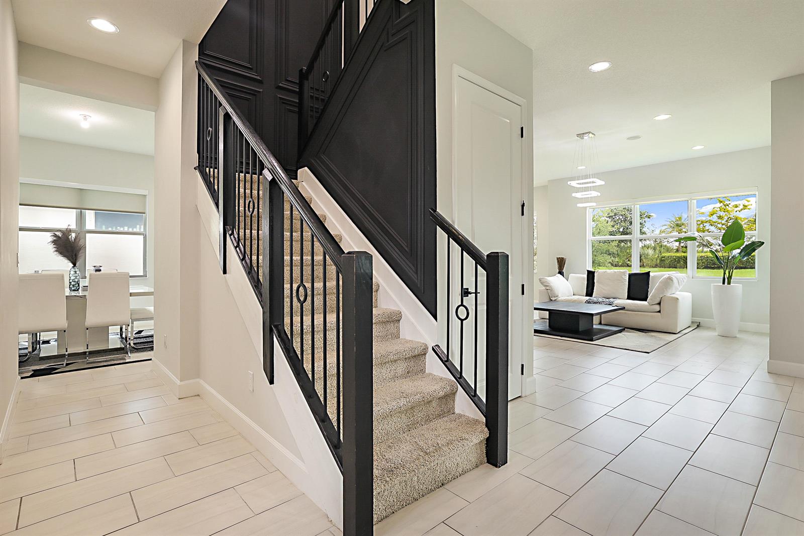 A staircase with black railings and trim sits between a dining area and living room — 16088 Orchard Drive, FL 33470, FL