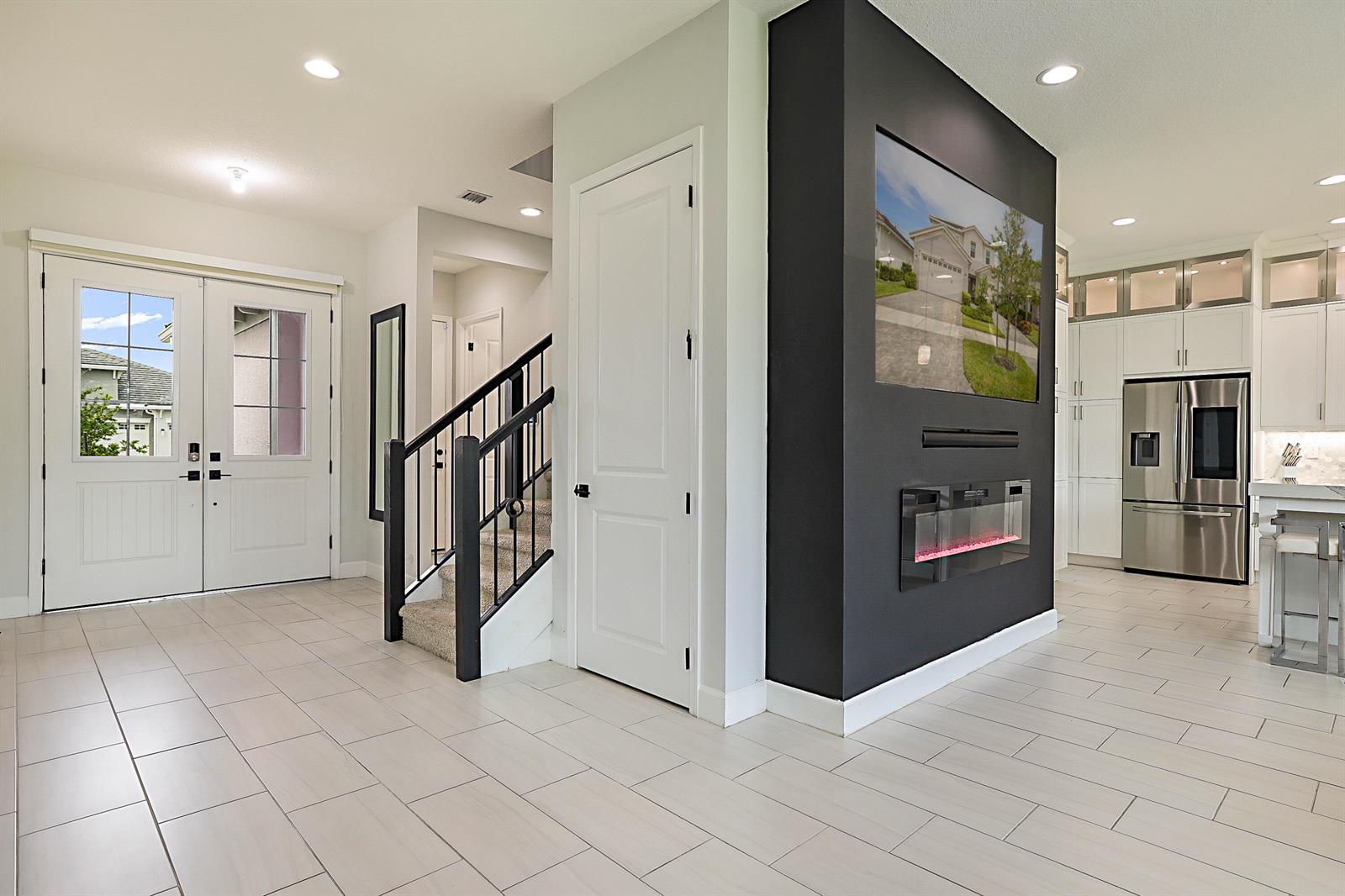 A foyer with tile floors, a staircase, and a black accent wall with a fireplace — 16088 Orchard Drive, FL 33470, FL