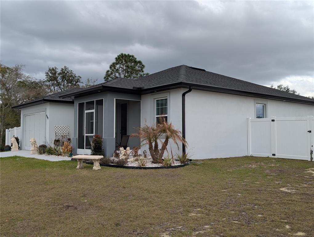 A single-story house with a white exterior, dark roof, and a screened-in front entryway — 400 MIAMI WAY, POINCIANA, FL