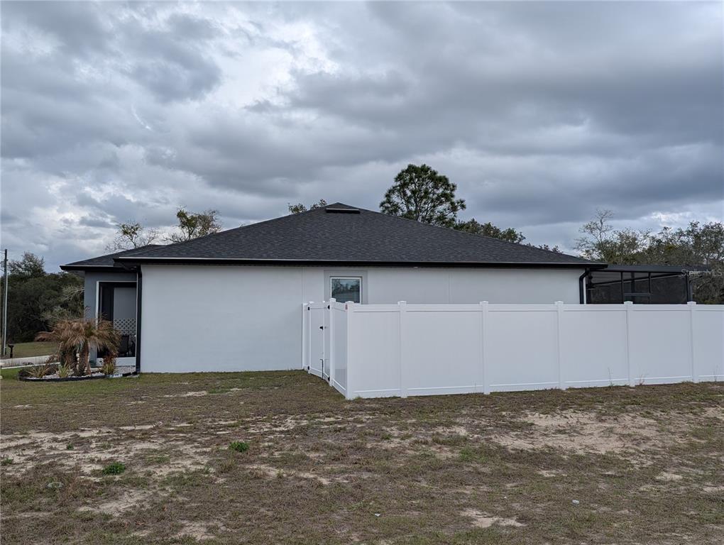 The exterior of a single-story house features a white wall, a dark roof, and a fence — 400 MIAMI WAY, POINCIANA, FL