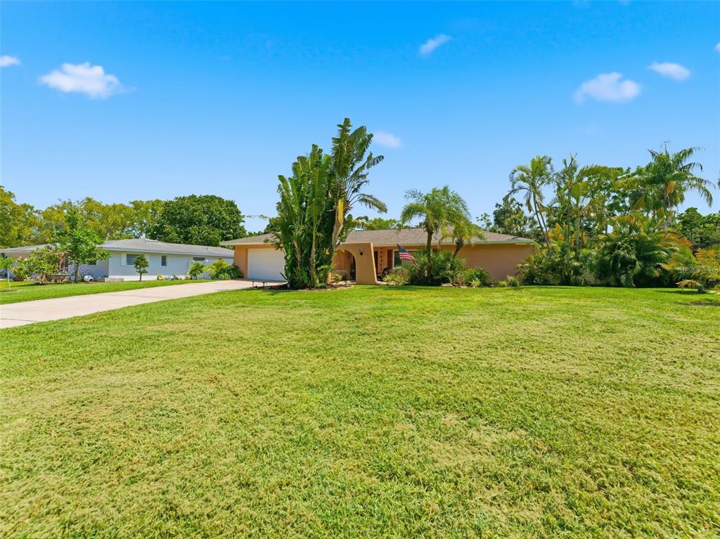 A single-story house with a tan exterior, a two-car garage, and a large front lawn — 3325 SAN MATEO STREET, CLEARWATER, FL