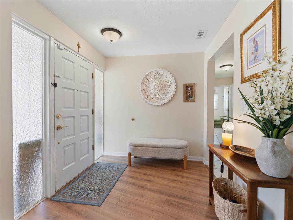 An entryway features wood-look flooring, a white front door, a bench, and a console table — 3325 SAN MATEO STREET, CLEARWATER, FL