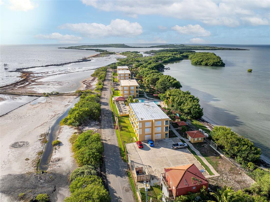 An aerial view shows a coastal road lined with apartment buildings and surrounding vegetation — SR 301 km 11.0 CONDOMINIO PLAYAS DEL CARIBE RESORT UNIT 303 - D, CABO ROJO, PR