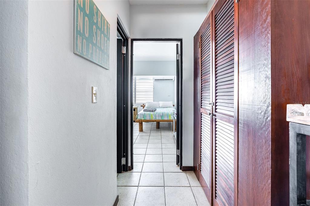 A hallway with tiled floors leads to a bedroom featuring a bed and louvered closets — SR 301 km 11.0 CONDOMINIO PLAYAS DEL CARIBE RESORT UNIT 303 - D, CABO ROJO, PR