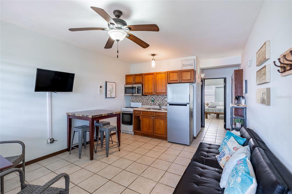A small kitchen and living area with tile floors, wooden cabinets, and a ceiling fan — SR 301 km 11.0 CONDOMINIO PLAYAS DEL CARIBE RESORT UNIT 303 - D, CABO ROJO, PR