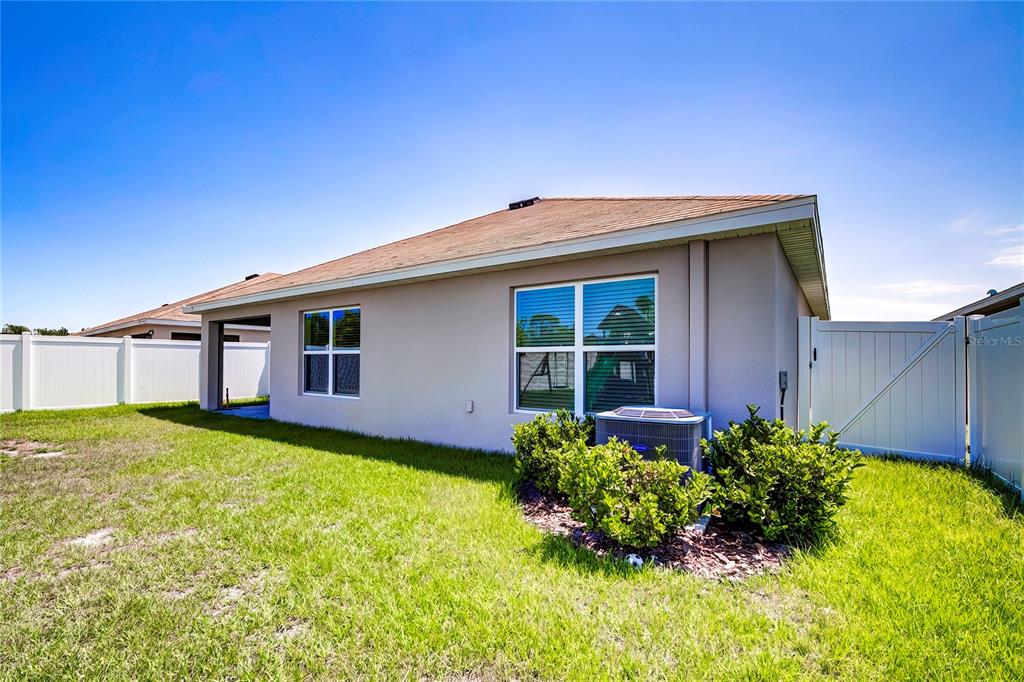 The exterior of a house features a tan stucco wall, a shingled roof, and landscaping — 4111 AUTUMN AMBER DRIVE, SPRING HILL, FL