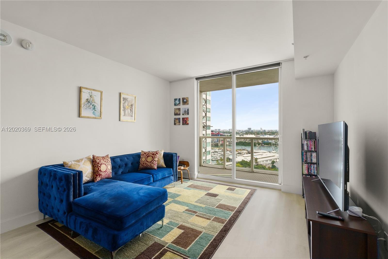 A living room features a blue velvet sectional, a patterned rug, and a balcony view — 253 NE 2nd St # 2003, Miami FL 33132, MIAMI, FL