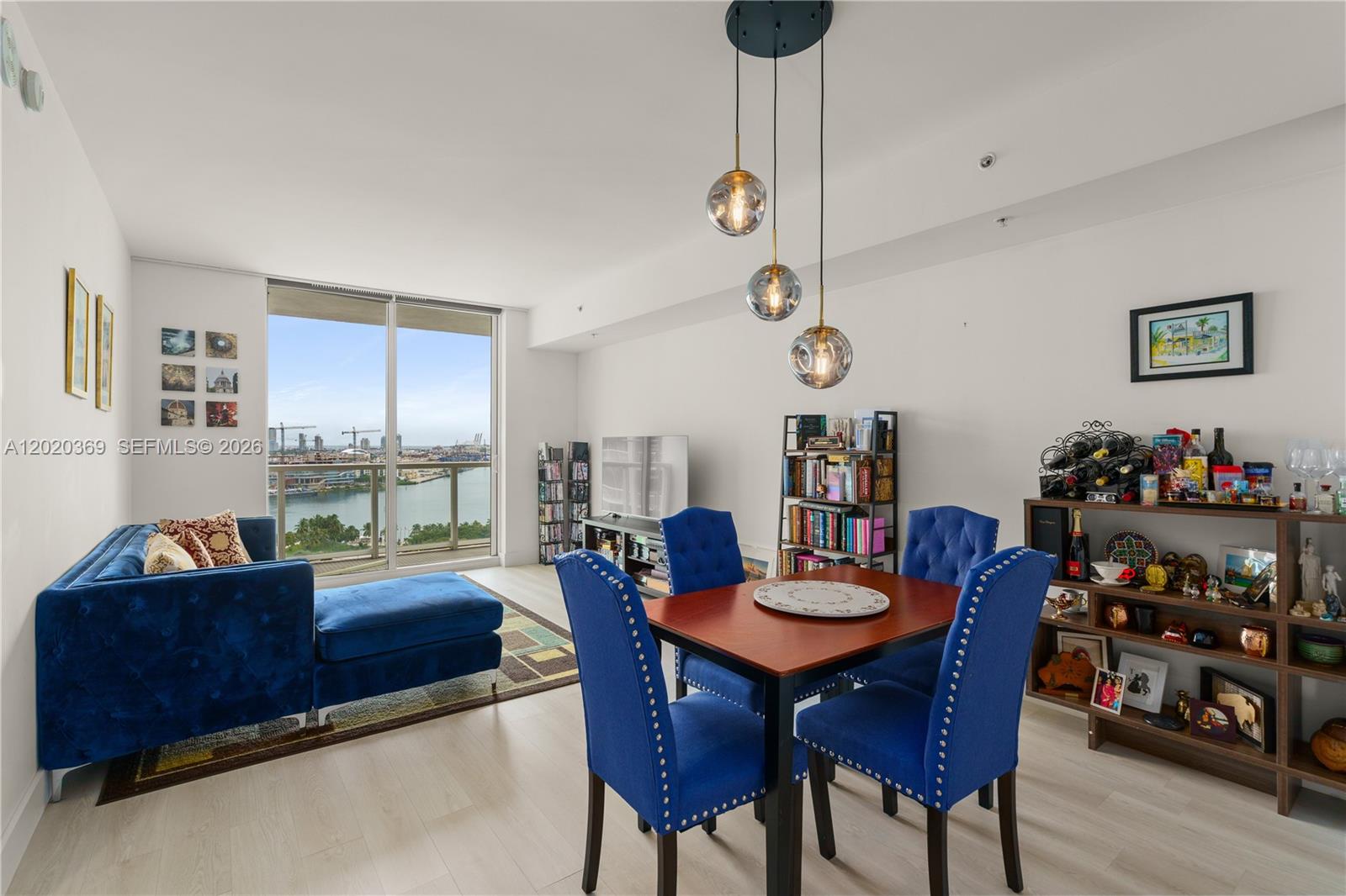 A living and dining area features blue velvet furniture, a wooden table, and floor-to-ceiling windows — 253 NE 2nd St # 2003, Miami FL 33132, MIAMI, FL