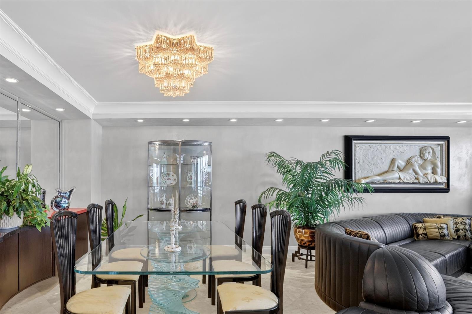 A dining area features a glass table, dark chairs, a crystal chandelier, and a display cabinet — 1400 S Ocean Boulevard # 1003, Boca Raton FL 33432, BOCA RATON, FL