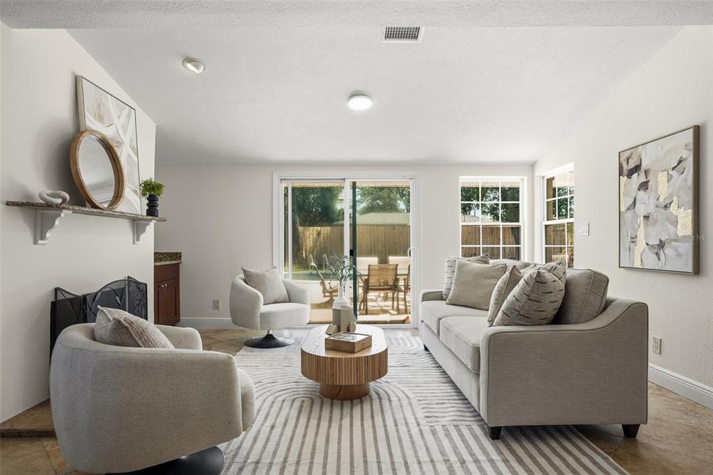 A living room features a fireplace, two swivel chairs, a sofa, and sliding glass doors — 2803 RIDDLE DRIVE, WINTER PARK, FL