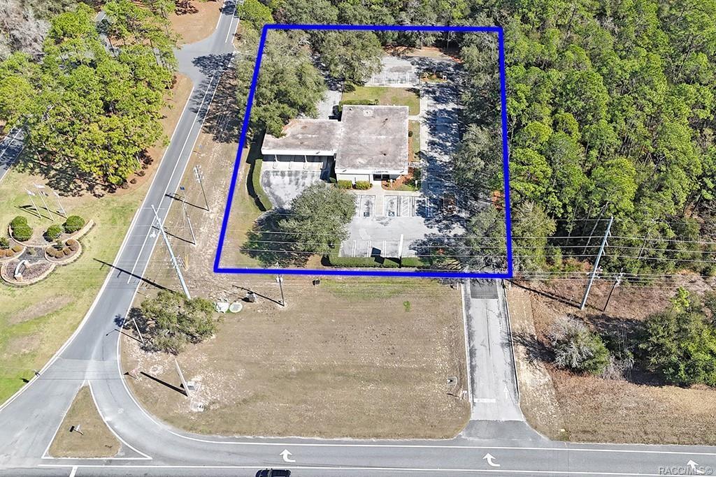 An aerial view shows a commercial building with a parking lot surrounded by dense trees — 10241 N FLORIDA AVENUE, CITRUS SPRINGS, FL