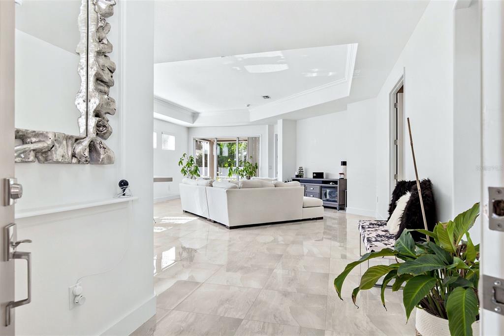 A bright living room features white tile floors, a sectional sofa, and a tray ceiling — 4316 CALLISTA LANE, SARASOTA, FL