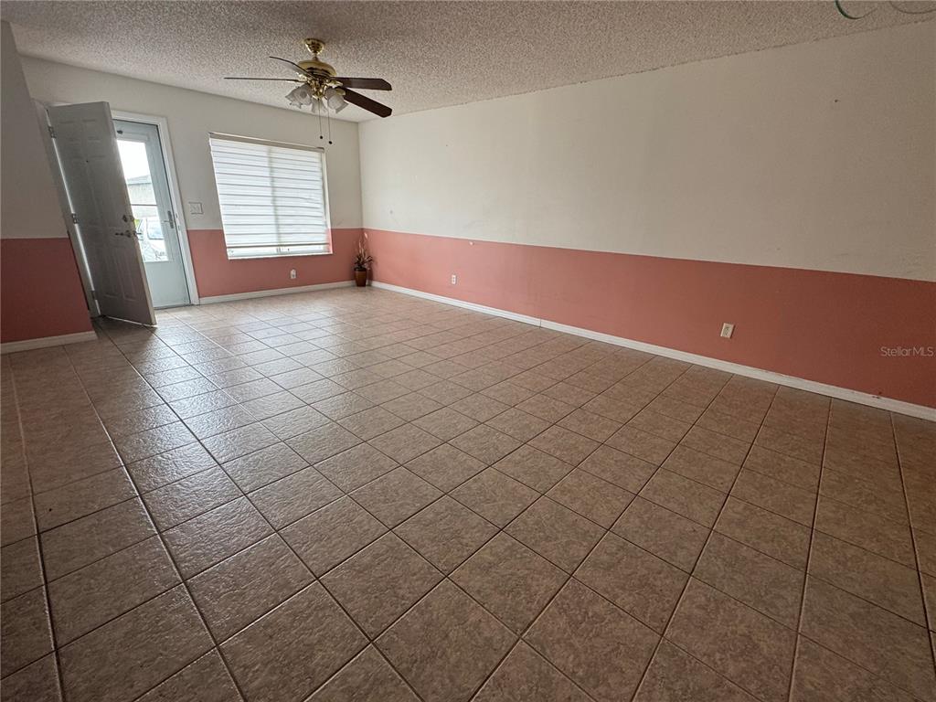 An empty room features beige tiled flooring, white and pink walls, and a ceiling fan — 344 WINTER RIDGE BOULEVARD UNIT 344, WINTER HAVEN, FL