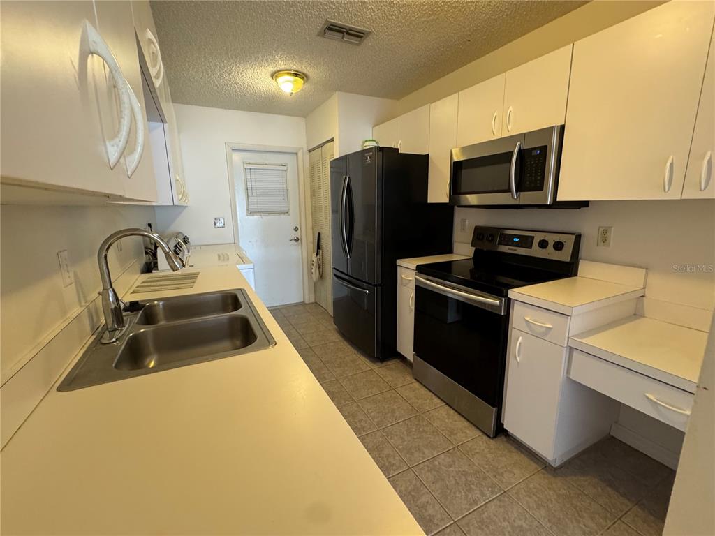 A kitchen with white cabinets, black appliances, a double sink, and tiled flooring — 344 WINTER RIDGE BOULEVARD UNIT 344, WINTER HAVEN, FL