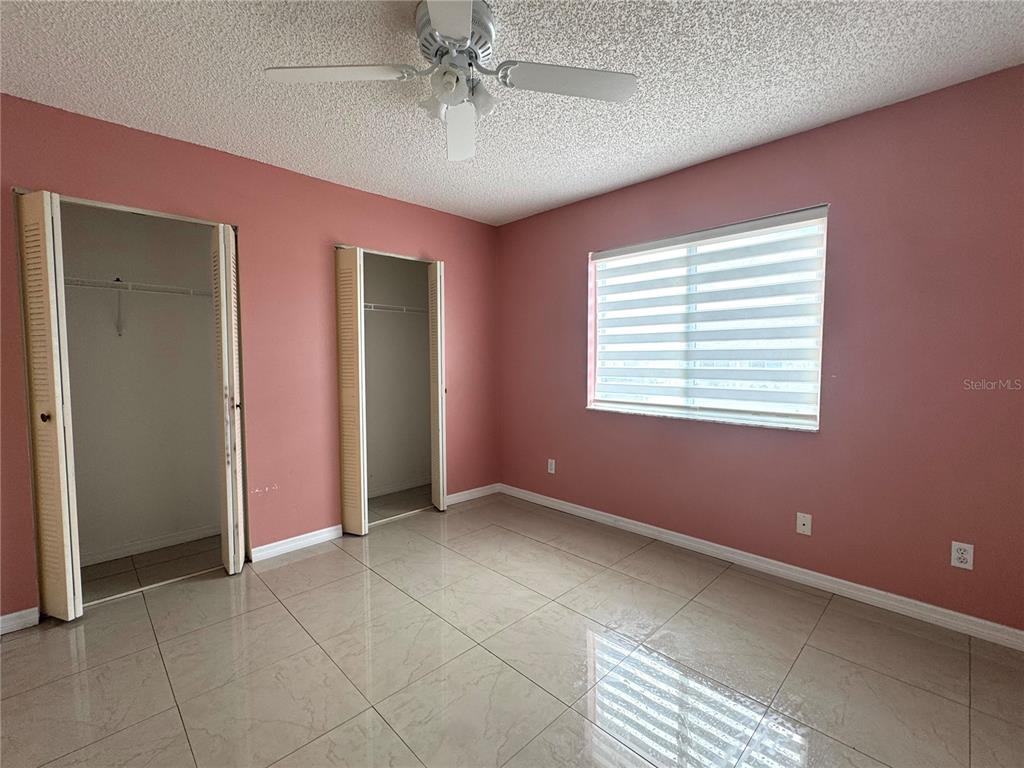 A bedroom features pink walls, tile flooring, two closets, and a ceiling fan — 344 WINTER RIDGE BOULEVARD UNIT 344, WINTER HAVEN, FL