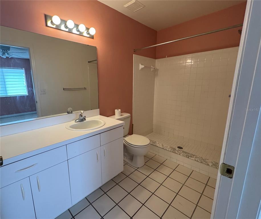 A bathroom with a white vanity, a toilet, and a tiled walk-in shower — 344 WINTER RIDGE BOULEVARD UNIT 344, WINTER HAVEN, FL