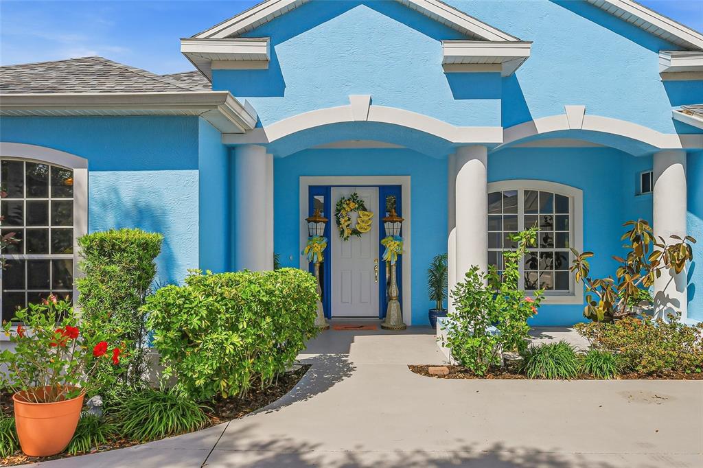 The exterior of a bright blue house features a covered entryway with white columns — 758 PLANTERS MANOR WAY, BRADENTON, FL